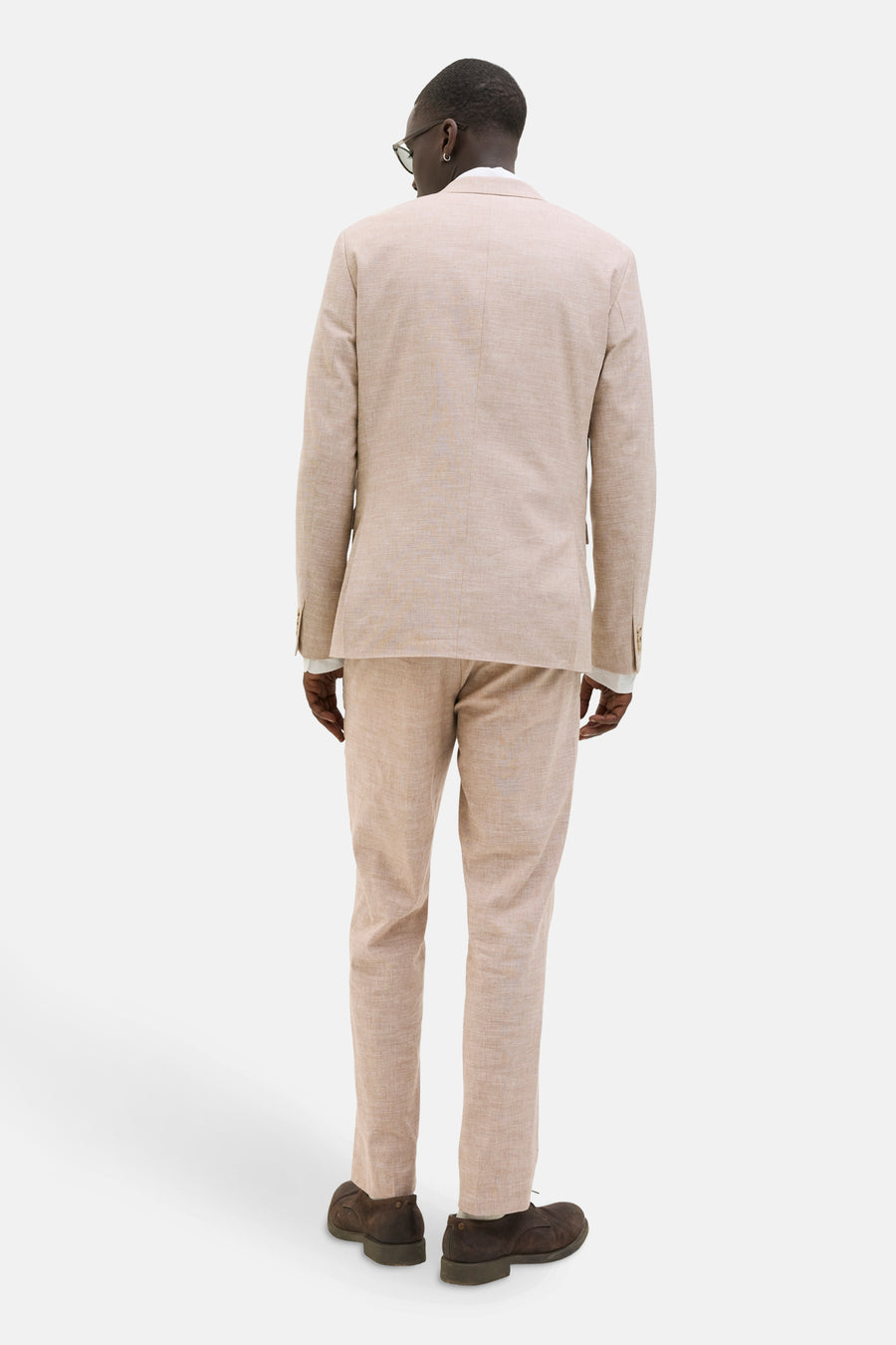 Man in beige linnen pak van achter.