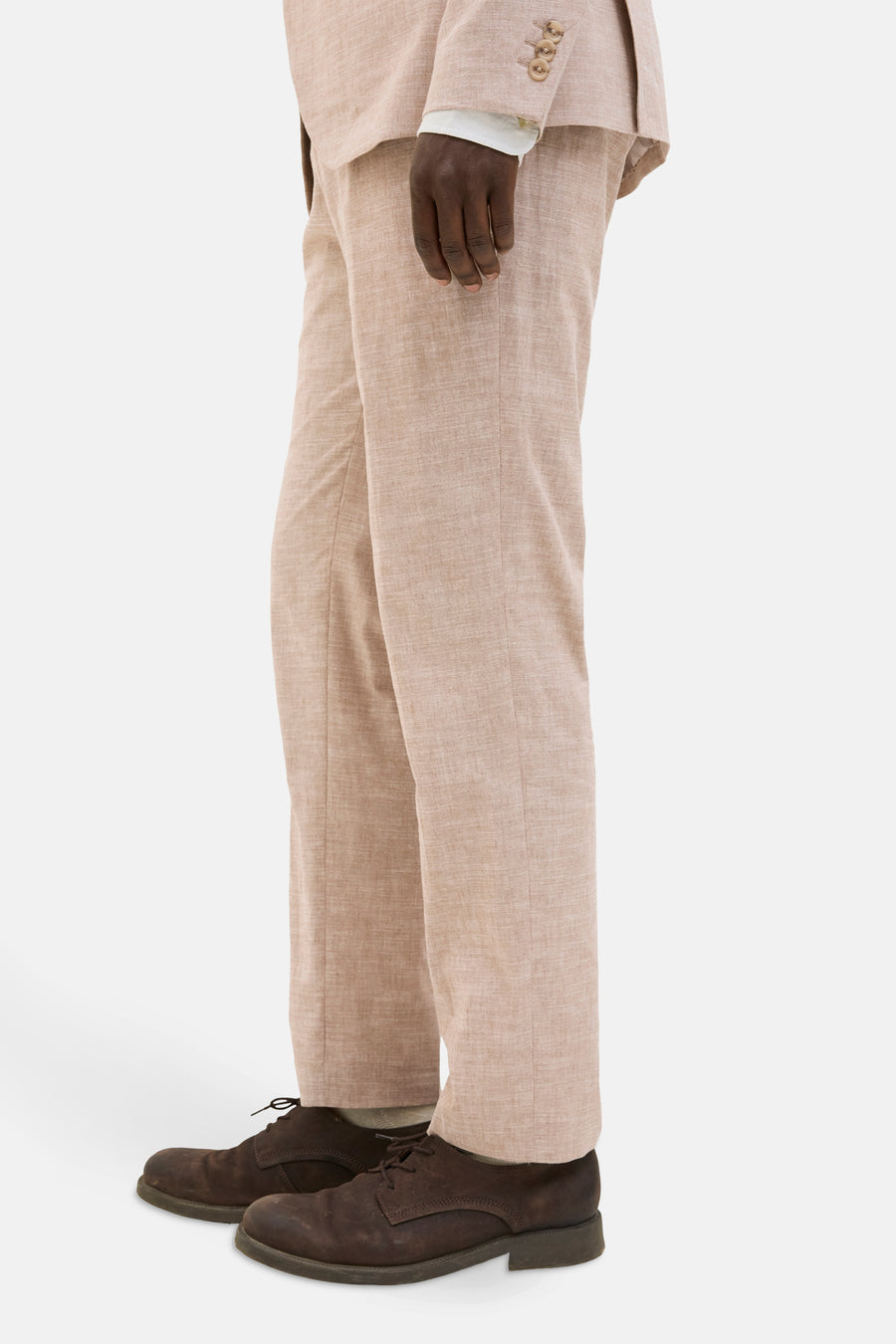 Olijfkleurig linnen pak met bruine schoenen, staand tegen een witte achtergrond.
