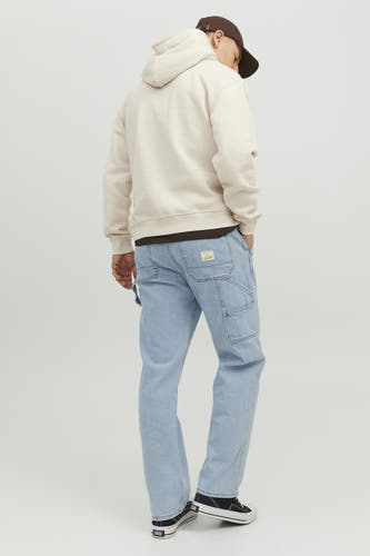 Jean en denim bleu clair large de JACK & JONES JEANS INTELLIGENCE, avec des poches de tailleur et des baskets noires.