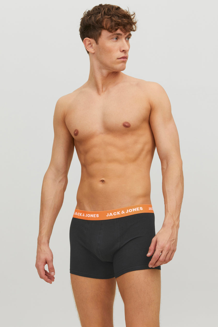 Mannelijk model met ontbloot bovenlijf, zwarte boxershort met oranje tailleband, Jack & Jones.