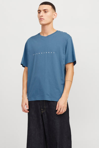 T-shirt bleu à manches courtes d'ORIGINALS BY JACK & JONES, avec le nom de la marque blanc sur la poitrine, porté avec un short en denim foncé.