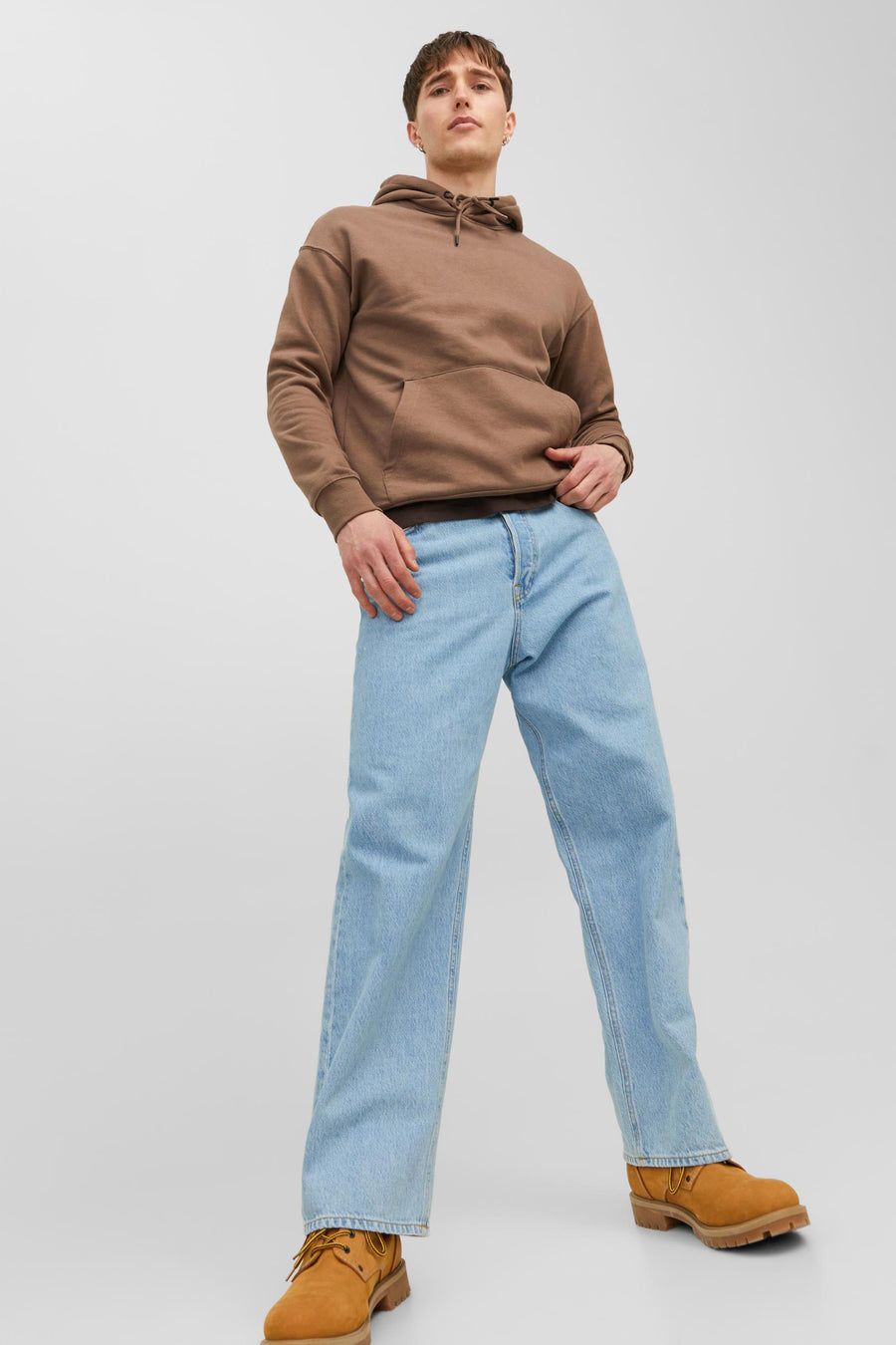 Jean en denim bleu clair large de JACK & JONES JEANS INTELLIGENCE, porté avec un pull marron et des chaussures marron.