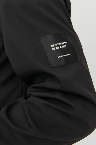 Close-up van een zwart kledingstuk met een label met coördinaten en "JACK&JONES©1990".