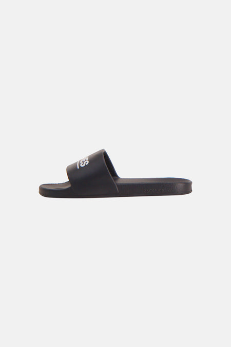 Zwarte slipper van JACK & JONES, met wit 'LES' logo op de band en 'JACK & JONES' op de zool, in zijzicht.