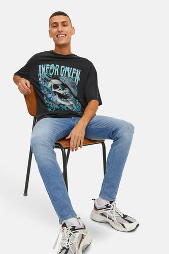 Jean skinny en denim bleu clair de JACK & JONES JEANS INTELLIGENCE, associé à un T-shirt noir imprimé et des baskets.