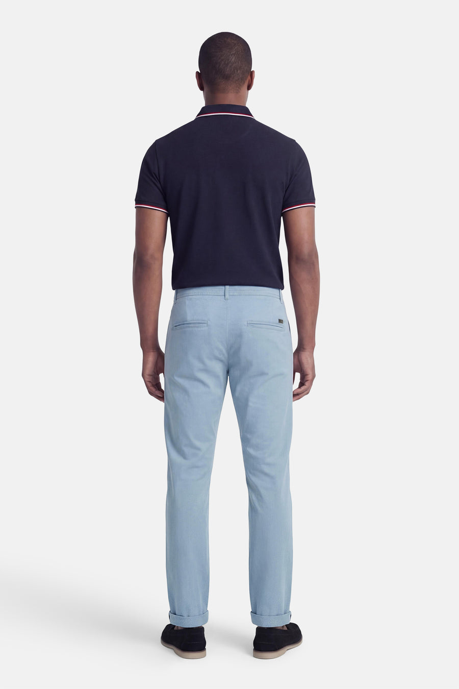 Blauwe chino van JACK & JONES JEANS INTELLIGENCE, gezien van achteren, met opgerolde pijpen en zwarte schoenen.