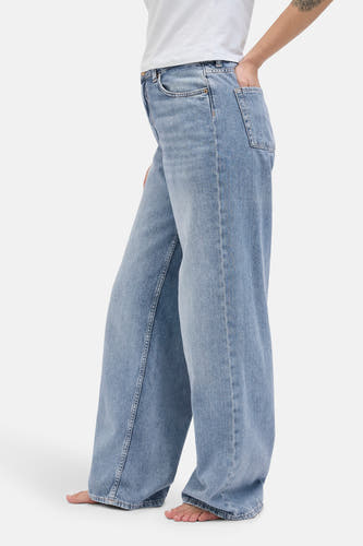 Jean bleu clair large de JJXX, avec une main dans la poche et un haut blanc.
