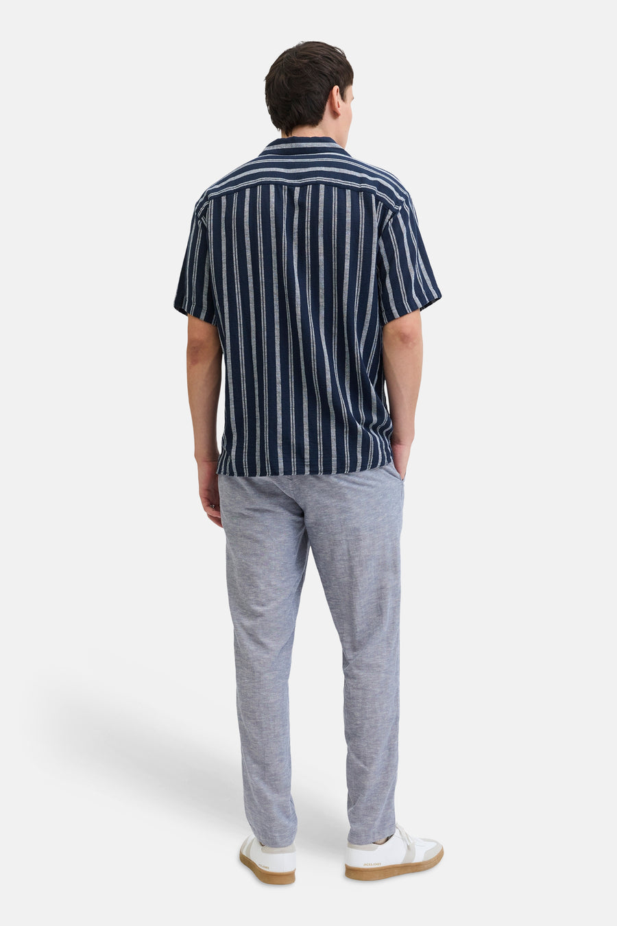 Chino bleu de JACK & JONES JEANS INTELLIGENCE, avec une texture légère, combiné avec une chemise rayée et des baskets blanches.