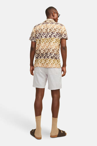 Short beige de JACK & JONES JEANS INTELLIGENCE, avec une légère texture, associé à un chemisier imprimé de fleurs.