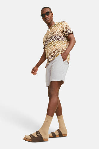 Short beige de JACK & JONES JEANS INTELLIGENCE, associé à une chemise à imprimé floral et des sandales brunes avec des chaussettes.
