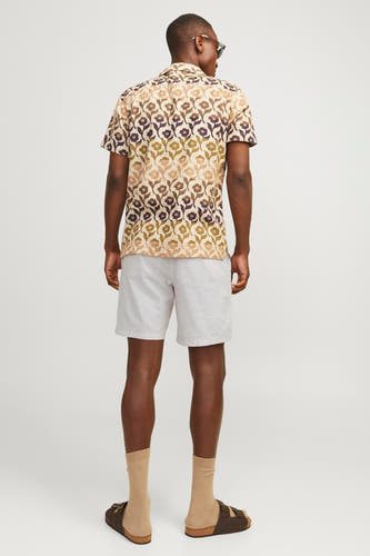 Short beige de JACK & JONES JEANS INTELLIGENCE, porté avec un t-shirt à fleurs, des chaussettes et des sandales, vu de derrière.