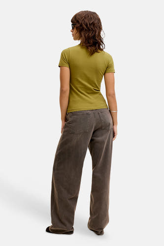 Groene korte mouwen t-shirt van JJXX, strak model, achterzijde, met donkere wijde broek en zonnebril