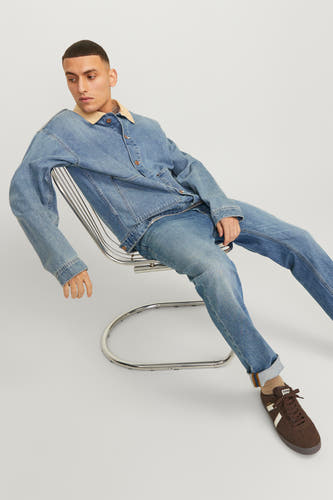Jean bleu moyen droit de JACK & JONES JEANS INTELLIGENCE, associé à une veste en denim avec un col beige et des baskets brunes.