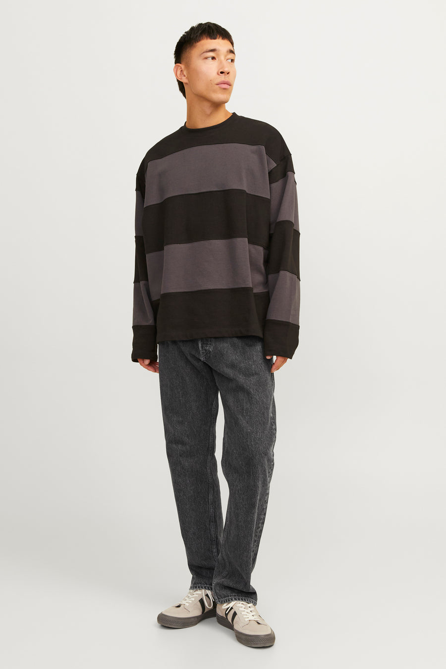 Jean délavé noir de JACK & JONES JEANS INTELLIGENCE, associé à une chemise rayée et des baskets crème.