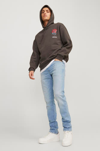 Lichtblauwe slim fit jeans van JACK & JONES JEANS INTELLIGENCE, gecombineerd met een bruine hoodie en witte sneakers.
