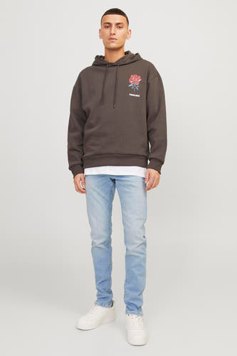 Lichtblauwe slim jeans van Jack & Jones Jeans Intelligence, met witte sneakers en een bruine hoodie.
