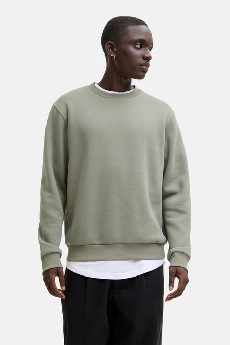 Pull vert avec col rond de CORE BY JACK & JONES, combiné avec un manteau beige et un pantalon noir.