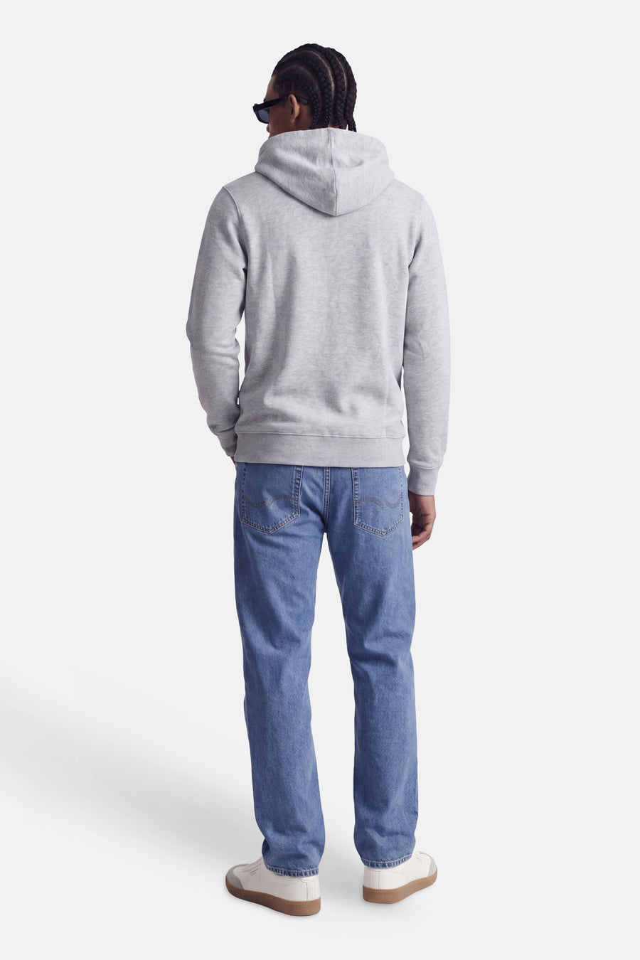 Sweat à capuche gris de CORE BY JACK & JONES, vue de dos, avec capuche et coupe confortable, porté avec un jean bleu et des baskets blanches.