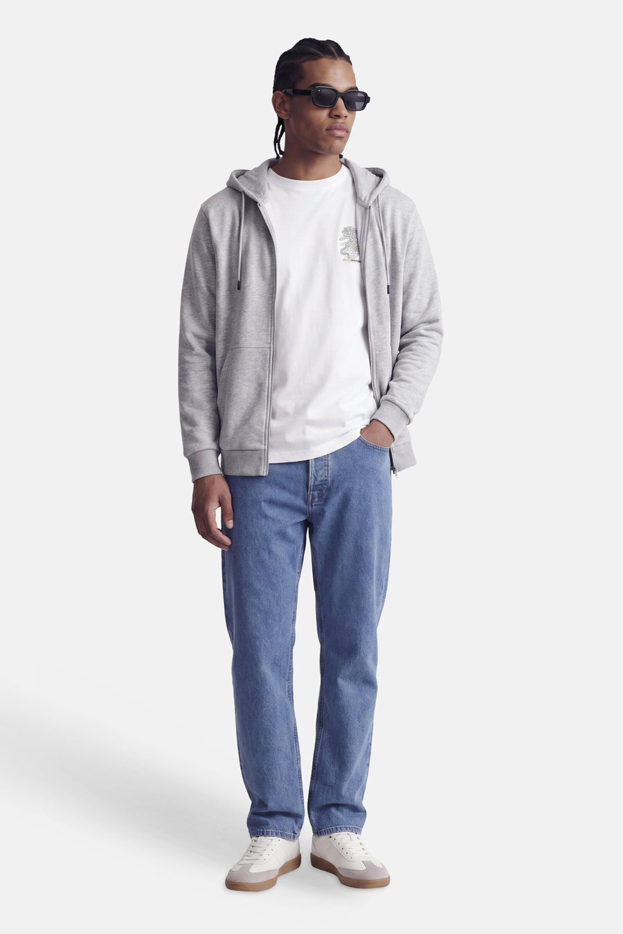 Sweat à capuche zippé gris de CORE BY JACK & JONES, avec capuche et poche avant, porté sur un t-shirt blanc, jean bleu et baskets blanches, vue de face.