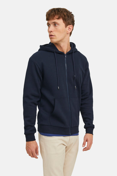 Veste bleue de CORE BY JACK & JONES, avec des manches longues et un capuchon, portée sur un t-shirt bleu et un pantalon beige.