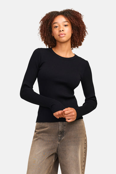 Pull noir à manches longues JJXX, avec des fines côtes et associé à un pantalon marron.