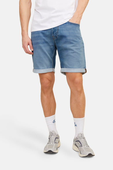Jean court en denim bleu marine de Jack & Jones, avec des poches surmontées et porté avec des chaussettes blanches et des baskets.