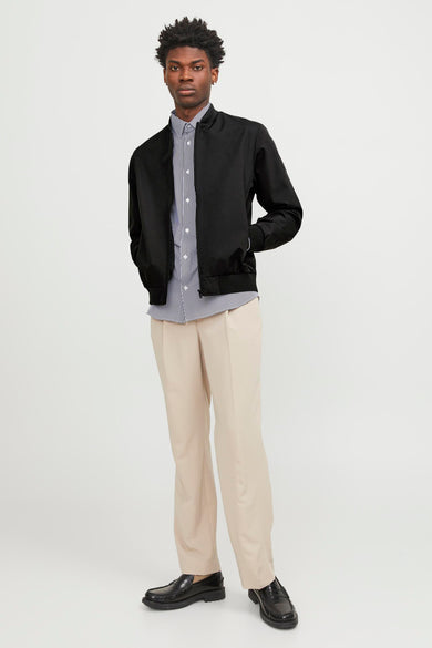 Manteau court noir de PREMIUM par JACK & JONES, porté avec un chemisier rayé et un pantalon beige.