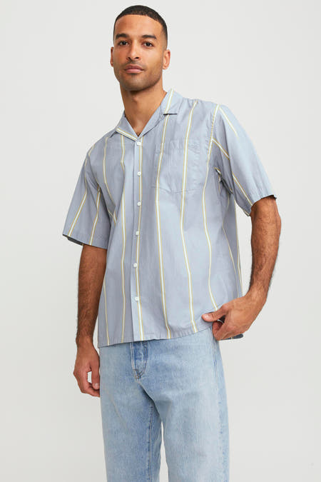 Chemise bleue à manches courtes de Royal Denim Division, rayée, associée à des jeans légers et des chaussures marrons.