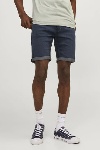 Donkerblauwe jeansshort van JACK & JONES JEANS INTELLIGENCE, met omgeslagen pijpen en gedragen met witte sokken en blauwe sneakers.
