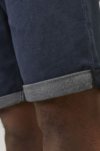 Donkerblauwe jeansshort van JACK & JONES JEANS INTELLIGENCE, met opgerolde zoom en detail van de been.