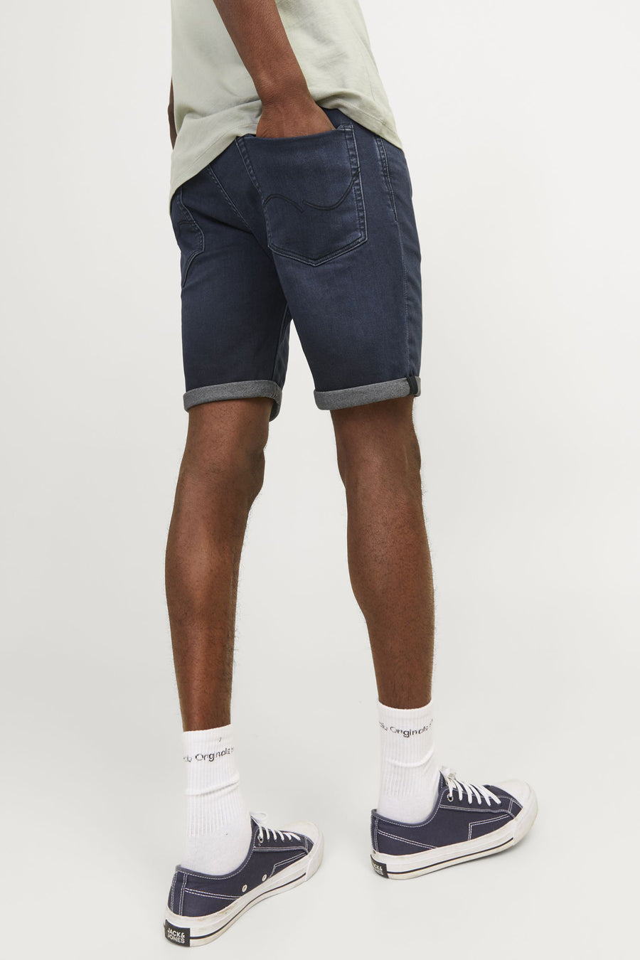 Donkerblauwe jeansshort van JACK & JONES JEANS INTELLIGENCE, met opgerolde pijpen en witte sokken met donkerblauwe schoenen.
