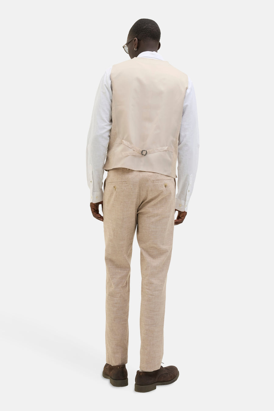 Beige gilet van PREMIUM by JACK & JONES, met verstelbare band op de rug, gedragen over een wit overhemd en beige broek.
