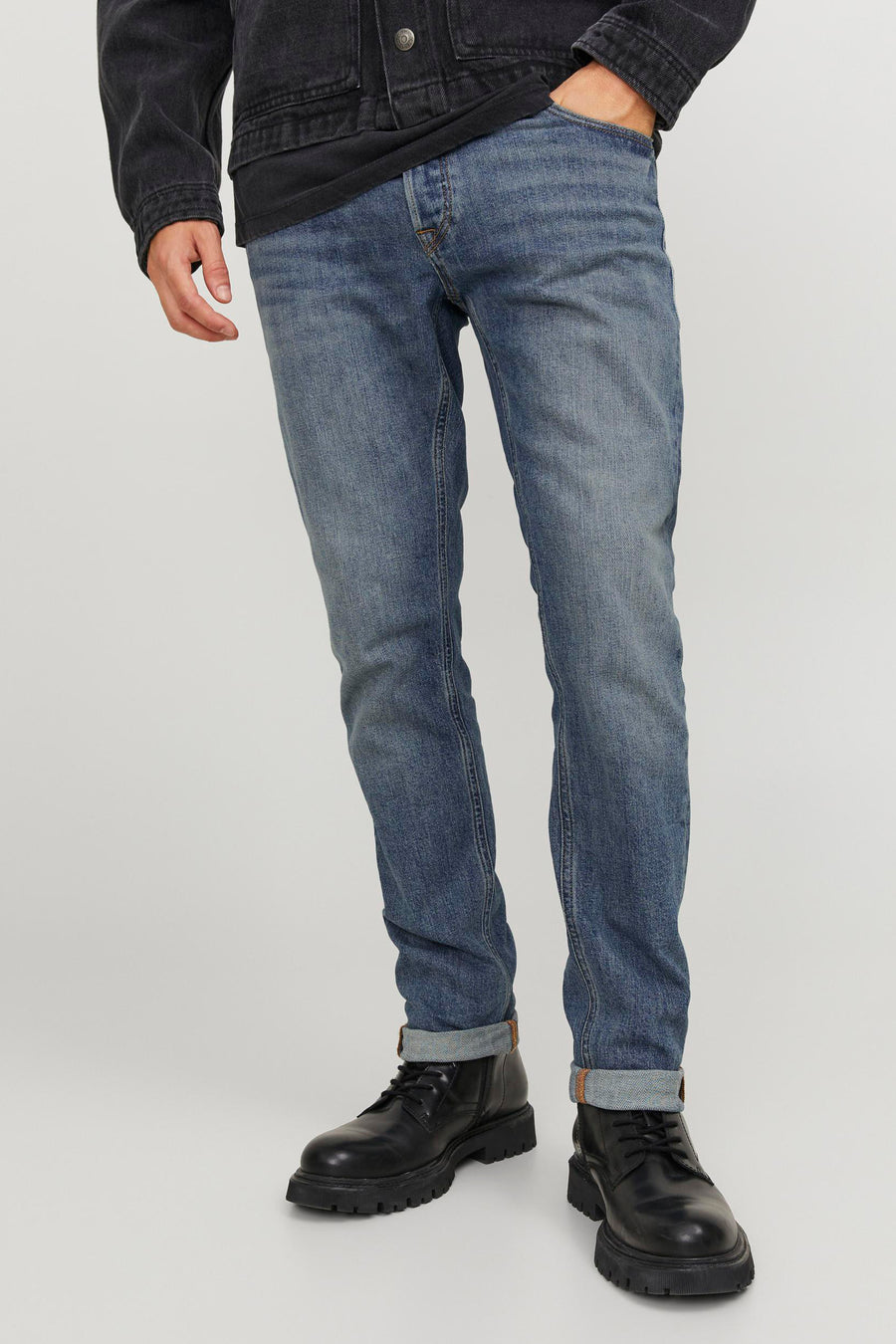 Man met blauwe jeans, zwarte jas en zwarte boots.