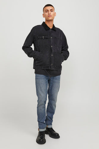 Man in zwart denim jack en blauwe jeans.