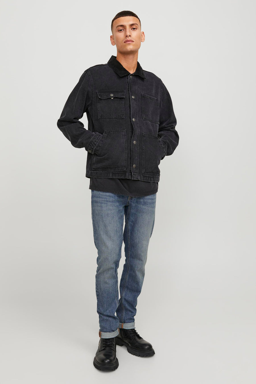 Man in zwart denim jack en blauwe jeans.