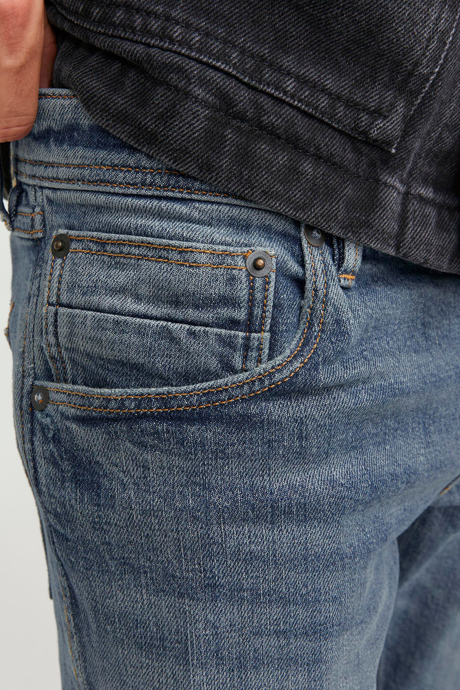 Close-up blauwe jeans met klein zakje en zwart denim jack.