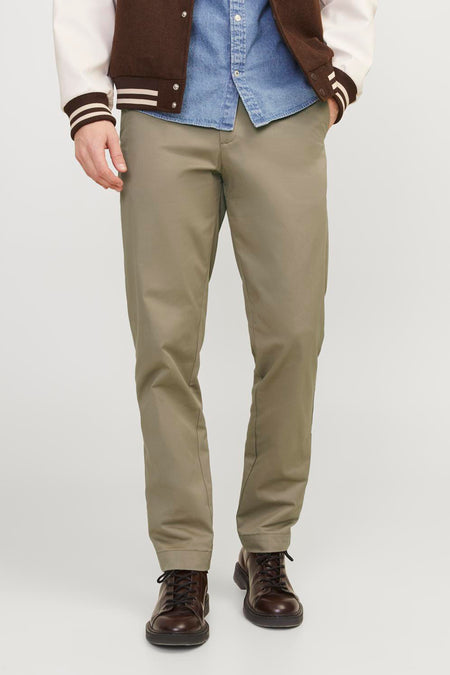 Chino beige de JACK & JONES JEANS INTELLIGENCE, combinée avec une chemise en jean, une veste universitaire et des chaussures marron.