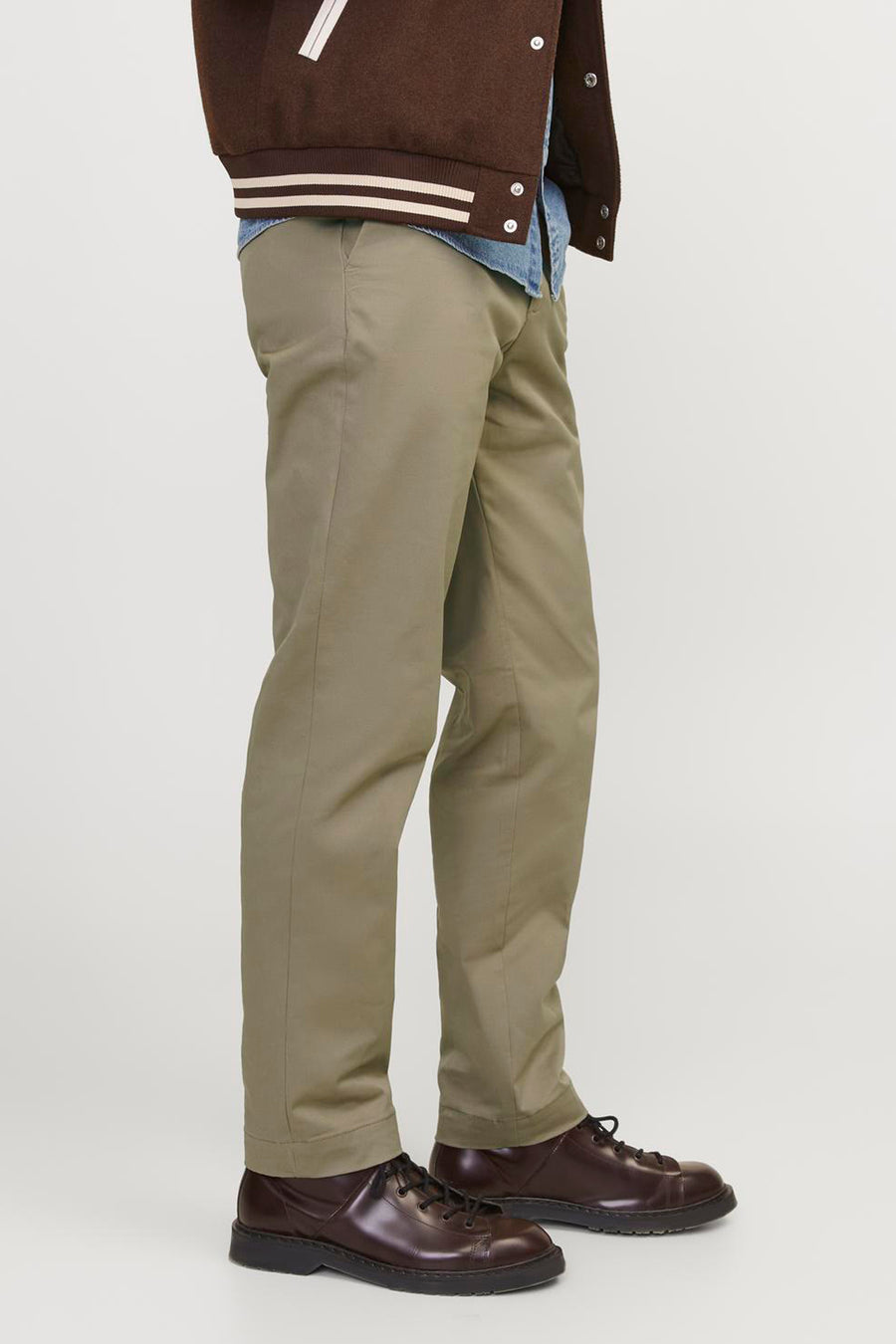Chino beige de JACK & JONES JEANS INTELLIGENCE, vue de côté sur un homme portant une veste universitaire marron et des chaussures marron foncé.