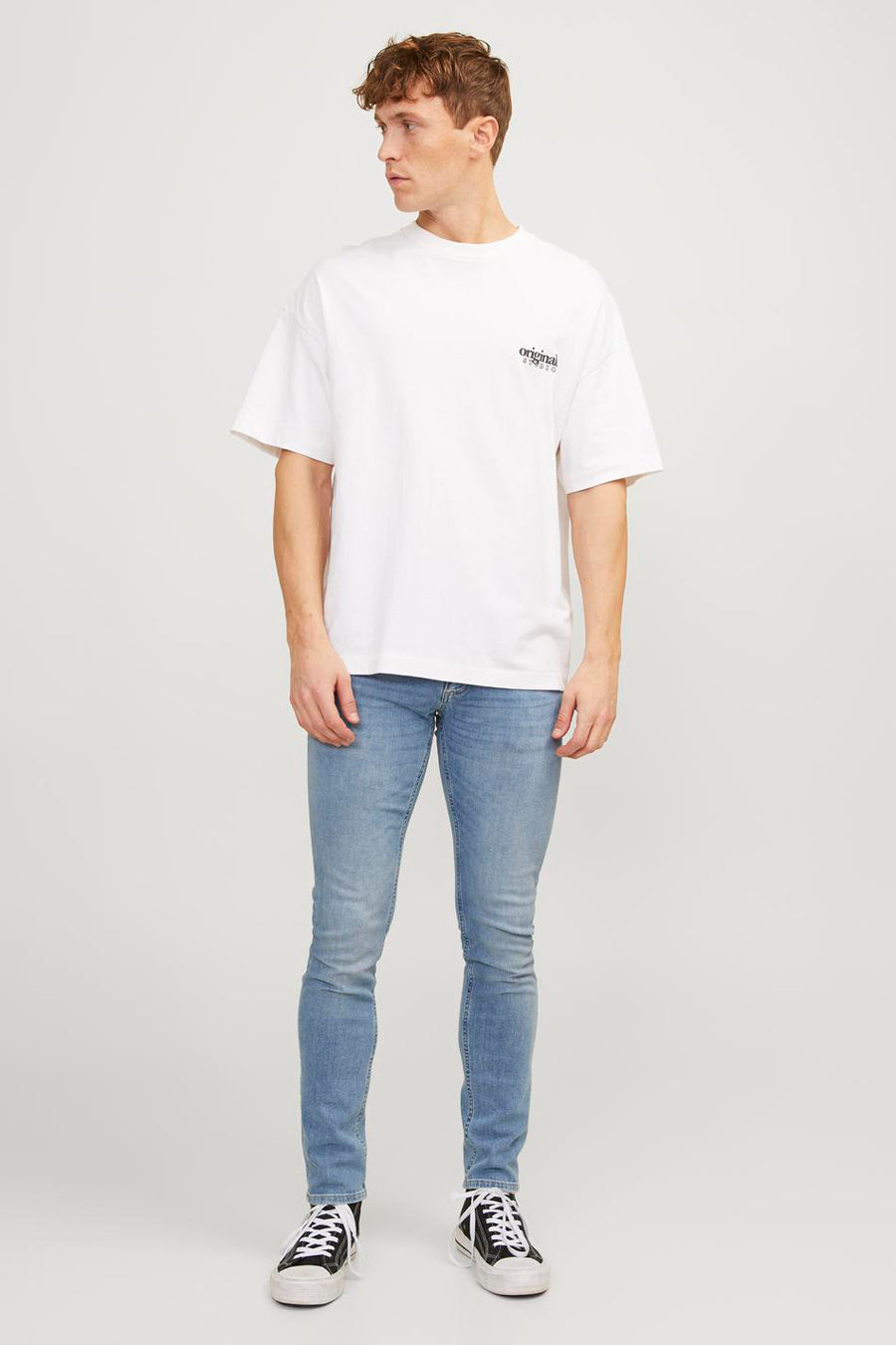 Jean skinny bleu clair de JACK & JONES JEANS INTELLIGENCE, associé à un T-shirt blanc et des baskets noires.