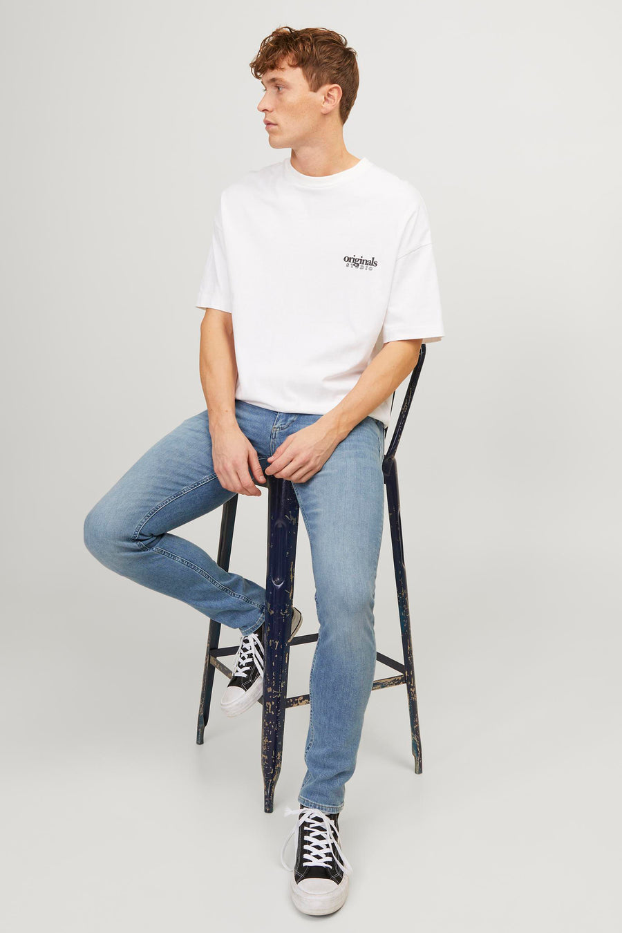 Jean skinny bleu clair de JACK & JONES JEANS INTELLIGENCE, porté avec un T-shirt blanc et des baskets hautes.