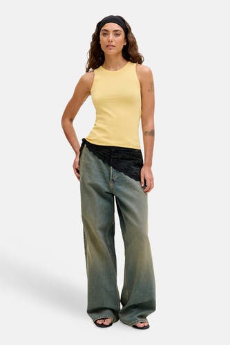 Haut sans manches jaune de JJXX, combiné avec un jean évasé à garniture en dentelle.