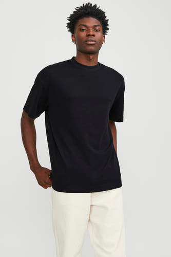T-shirt noir à manches courtes de CORE BY JACK & JONES, associé à un pantalon crème et des chaussures noires.