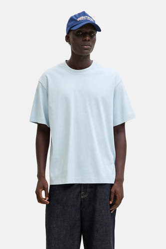 T-shirt bleu à manches courtes de CORE BY JACK & JONES, porté avec un chapeau bleu et des jeans larges, avec des baskets blanches.