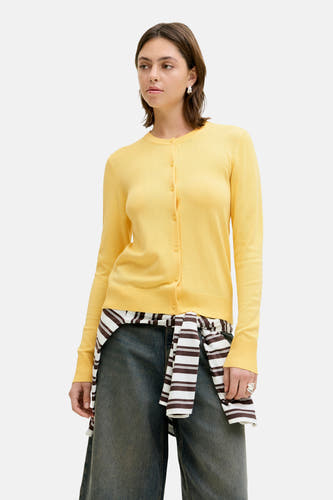 Cardigan jaune de JJXX, à manches longues et porté avec un pantalon culotte en jean et des bottes en cuir.