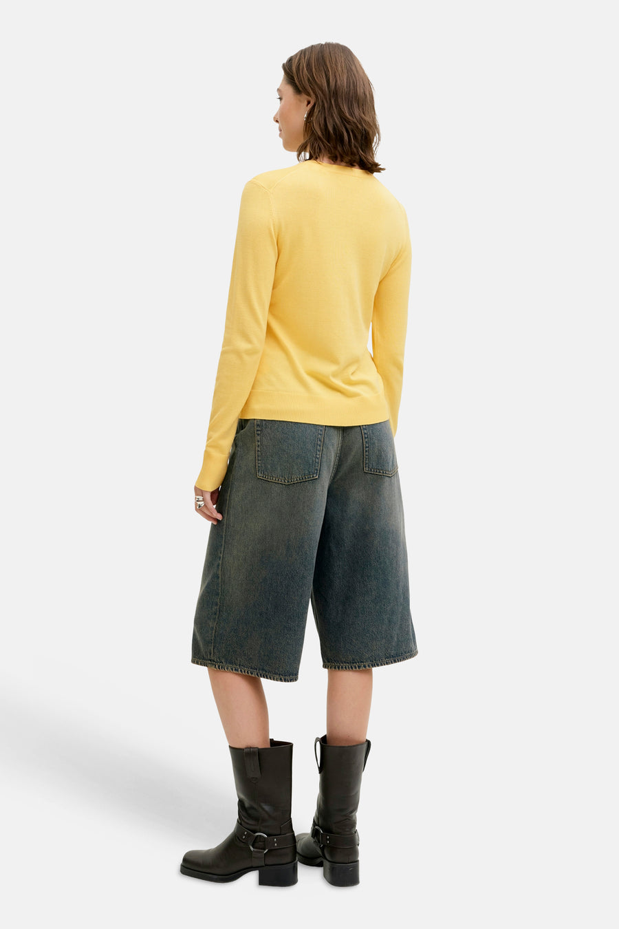 Gele cardigan van JJXX, met lange mouwen en gedragen met denim culottes en leren laarzen.
