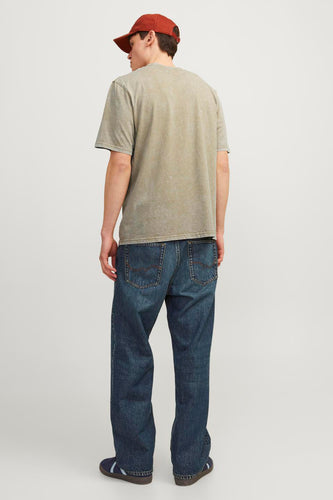 Man van achteren met spijkerbroek, T-shirt en pet.