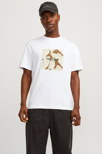 Een man met een donkerblauwe pet draagt een wit T-shirt met een bruine print en een donkergrijze broek.