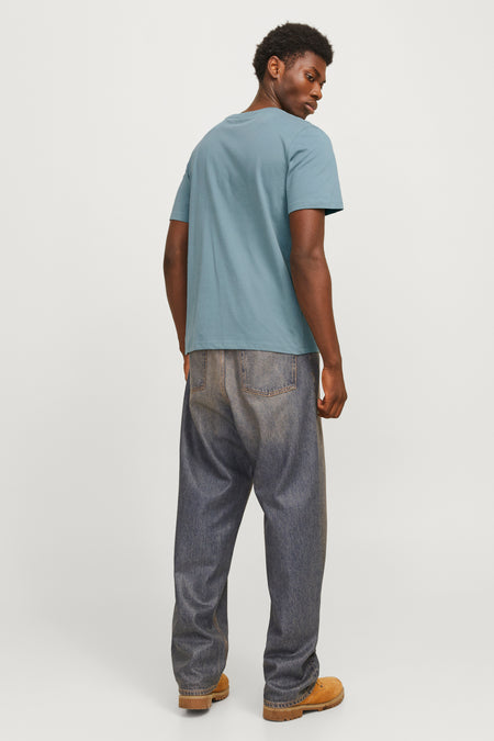 T-shirt bleu à manches courtes de CORE BY JACK & JONES, vu par derrière, associé à des jeans larges et des bottes marron.