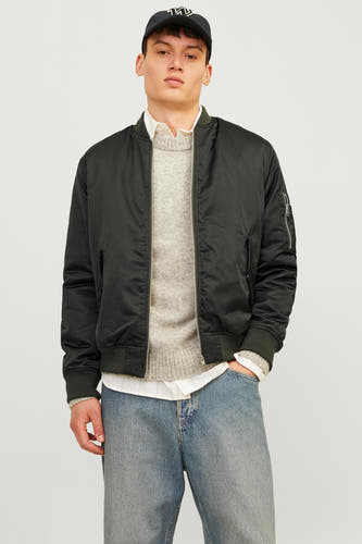 Veste courte verte de CORE BY JACK & JONES, portée avec un pull et une chemise blanche, associée à des jeans bleus et des baskets marrons.