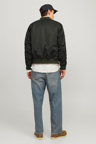 Veste verte de CORE BY JACK & JONES, avec des manches longues, portée sur un chemisier blanc et des jeans bleus.